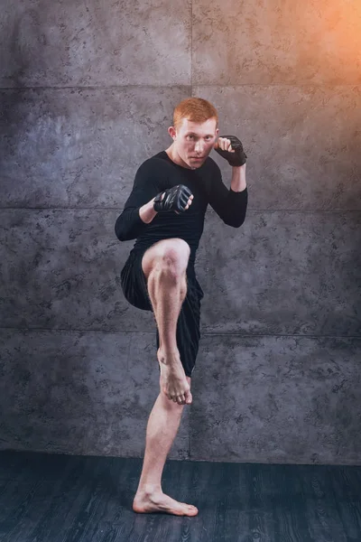 Young fighter posing in studio before grey wall