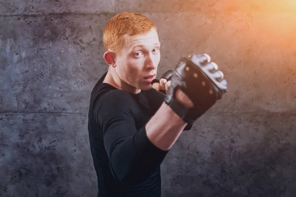 Young fighter posing in studio before grey wall