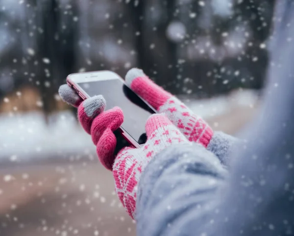 Woman using smartphone with pink gloves for touch screens in winter.