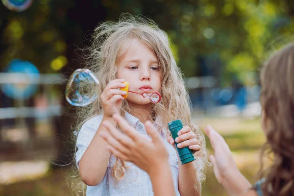 Little girl with bubble blower in park.