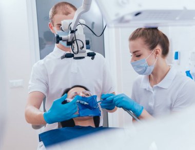 Mikroskop altında tedavisinde kök kanallar, asistan ile çalışma. Modern teknoloji