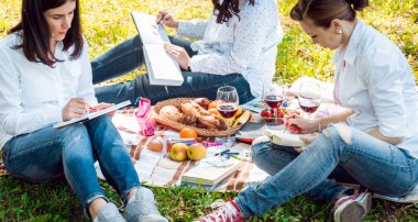Sketchbooks piknik üzerinde yeşil park ile genç kızlar