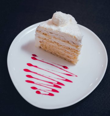 Siyah masa örtüsü üzerinde beyaz tabakta kremalı pasta