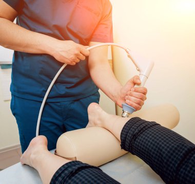 Şok dalga tedavisi. Manyetik alan, rehabilitasyon. Fizyoterapist doktor ameliyat hastalar topuk üzerinde gerçekleştirir.