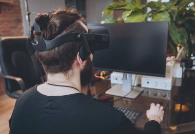 Sanal gerçeklik giyen sakallı genç adam ofiste gözlükler