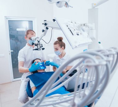 Mikroskop altında tedavisinde kök kanallar, asistan ile çalışma. Modern teknoloji