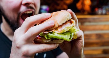 Genç adam yeme cheeseburger Restoran