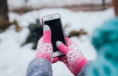 Smartphone ile pembe eldiven dokunmatik ekranlar için kışın kullanan kadın.