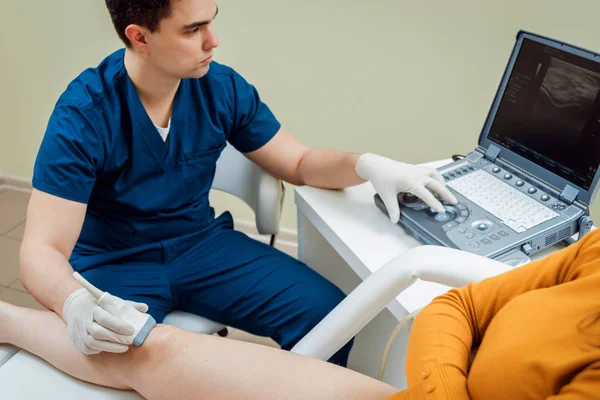 Ortopedi uzmanı doktor ofisinde hastayla. Diz ultrason.