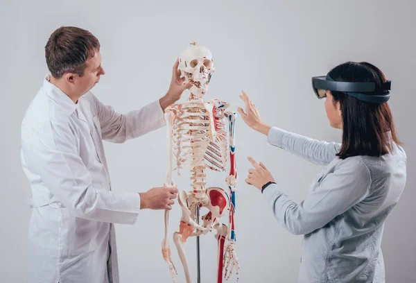 医生使用增强现实护目镜和人体骨架教学学生 — 图库照片