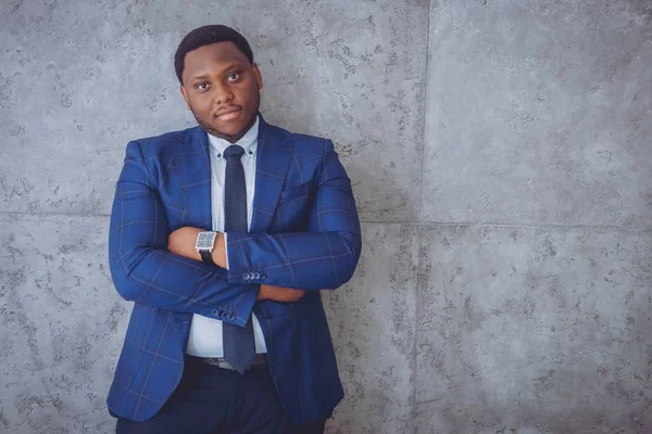 African american businessman in blue suit standing near the gray wall