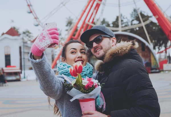 Couple using smartphone with gloves for touch screens in winter