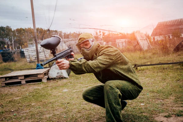 Man with gun playing at paintball. Outdoors.
