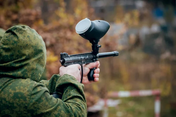 Man with gun playing at paintball. Outdoors.