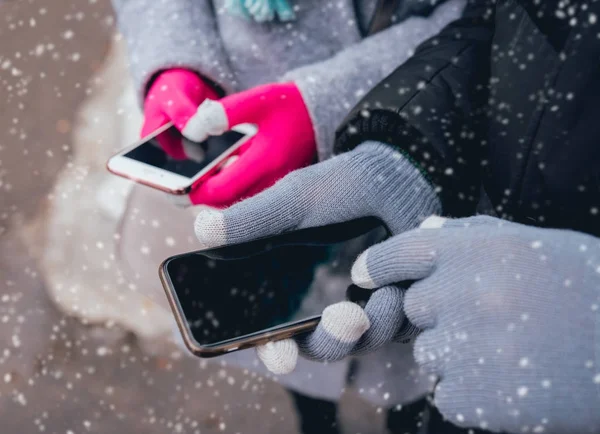 Couple using smartphone with gloves for touch screens in winter