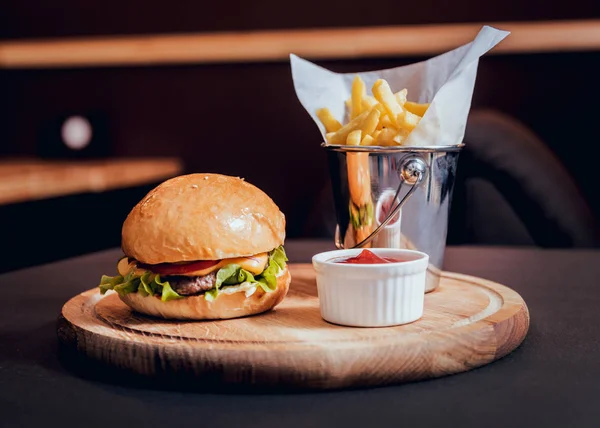 Ahşap masa üzerinde yangınları ile büyük ve lezzetli burger. — Stok fotoğraf
