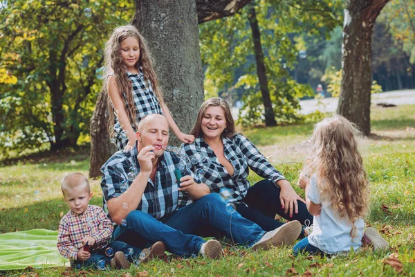 Genç aile ve kabarcık üfleyiciler Park ile neşeli çocuklar.