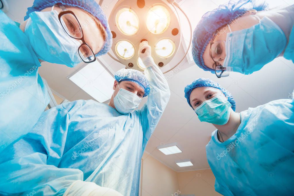 Group of surgeons in operating room with surgery equipment. 