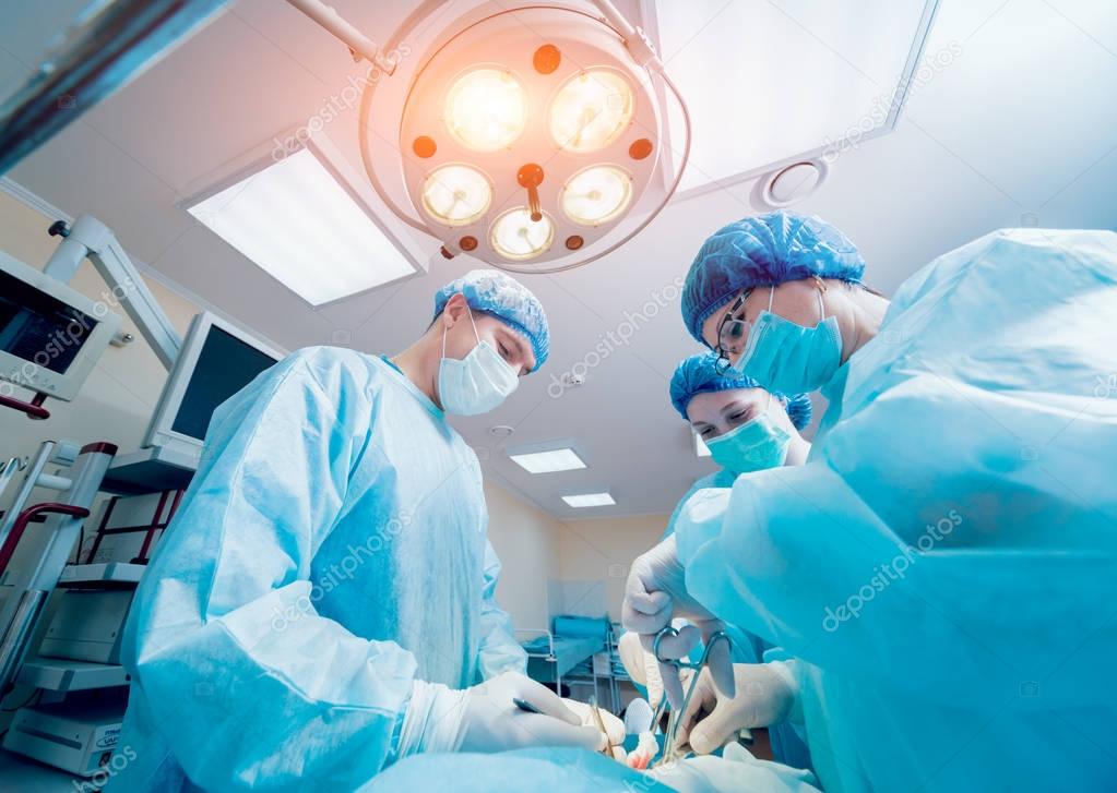 Group of surgeons in operating room with surgery equipment. Background 