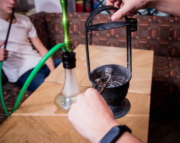 Cooking hookah in the bar. Young man with hookah in restaurant, hookah bar, smoking cafe.