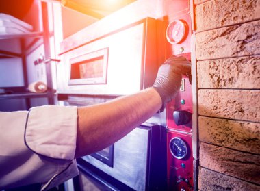 Pizza yapma süreci. Şef fırıncı çiğ pizzayı fırına koyar. Mutfak..