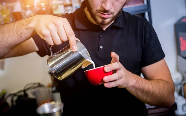 Barista dělá cappuccino kávu nalévání mléka. — Stock fotografie