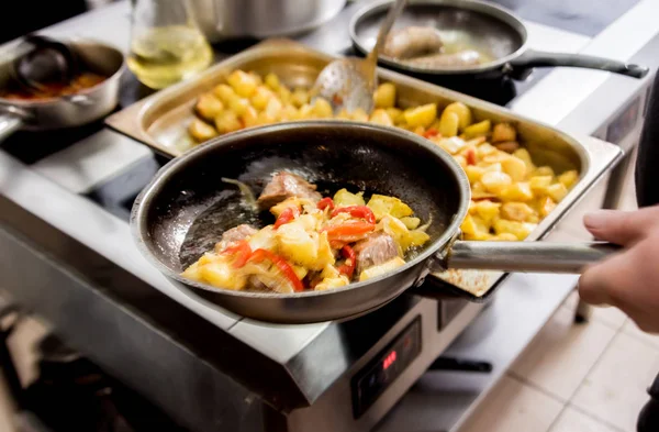 Chef cuisinier pommes de terre frites avec des morceaux de viande dans une cuisine de restaurant — Photo