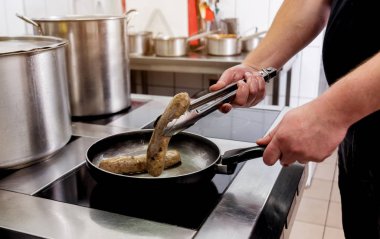 Tavada sosis pişirmek. Tavada ızgara sosis. Restoran.