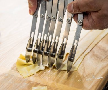Şef makarna makinesiyle hamur topluyor. Makarna makinesi. Ev yapımı İtalyan mutfağı. Restoran.