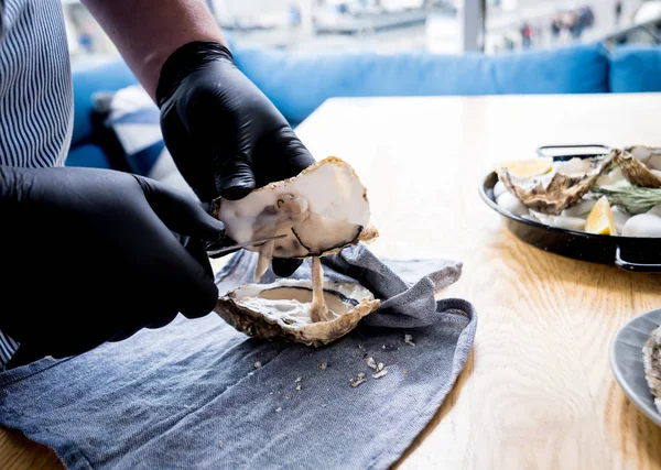 Chef ouvre une huître fraîche. Plat avec huîtres ouvertes. Restaurant . — Photo