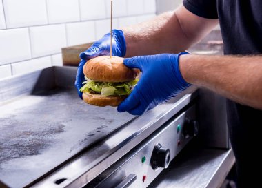 Şef mutfakta ızgara ocağında hamburger hazırlıyor. Restoran.
