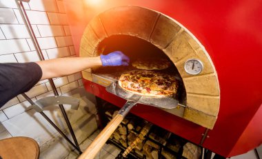 Pizza yapma süreci. Şef fırıncı çiğ pizzayı fırına koyar. Mutfak..