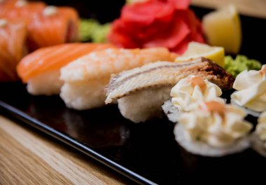 Suşi seti. Tahta bir tabakta somon, yılan balığı ve kırmızı havyarla yuvarlanıyor. Restoran.