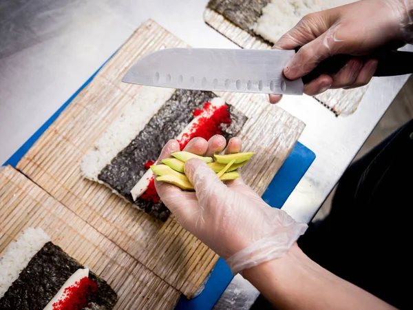 Restoranın mutfağında suşi ve ekmek yapma süreci. Şefin elleri bıçaklı..