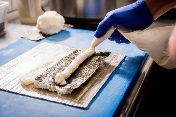 Proces van het maken van sushi en broodjes in restaurant keuken. Chefs handen met mes. — Stockfoto