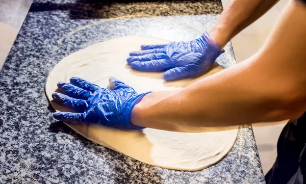 El proceso de hacer pizza. Manos de cocinero panadero haciendo pizza en la cocina cafetería — Foto de Stock