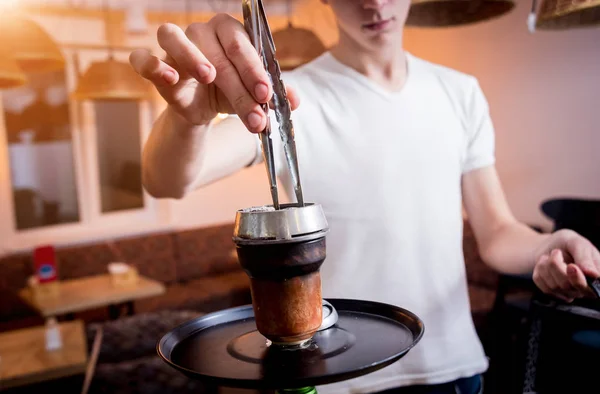 Cooking hookah in the bar. Young man with hookah in restaurant