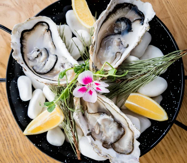 新鲜的牡蛎放在有冰块和花朵的盘子里. 餐馆 — 图库照片