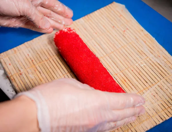 Proceso de hacer sushi y rollos en la cocina del restaurante. Chefs manos con cuchillo . — Foto de Stock