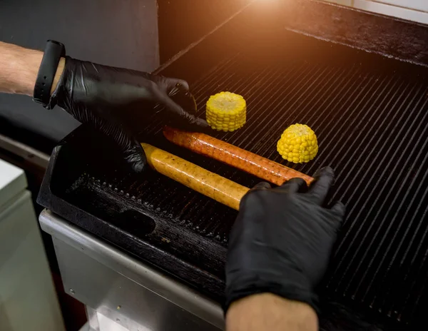 Le chef cuisine deux hot-dogs sur un gril. Restaurant . — Photo