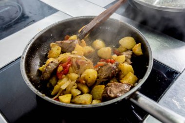 Şef, restoranın mutfağında kızarmış patates pişiriyor.