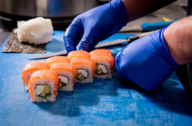 Restoranın mutfağında suşi ve ekmek yapma süreci. Şefin elleri bıçaklı..