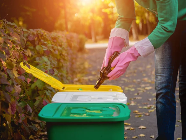 Volunteer girl sorts garbage in the street of the park. Concept of recycling.