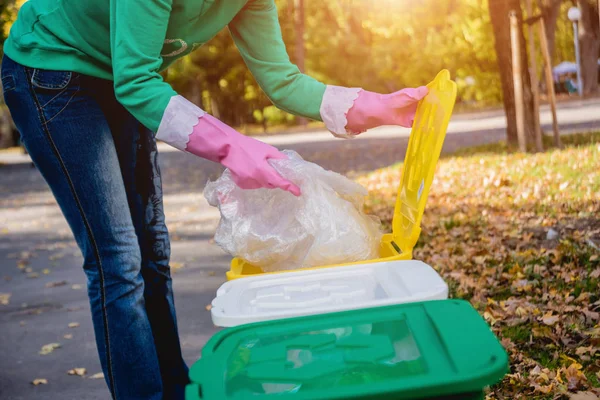 Volunteer girl sorts garbage in the street of the park. Concept of recycling. — ストック写真