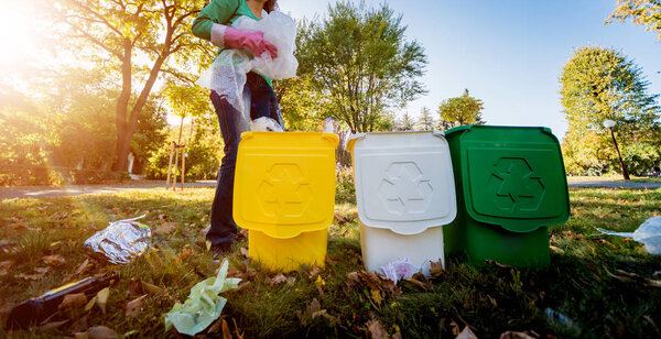 Девушка-волонтёр сортирует мусор на улице парка. Концепция переработки

