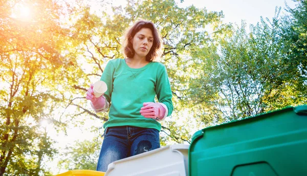 Девушка-волонтёр сортирует мусор на улице парка. Концепция переработки — стоковое фото