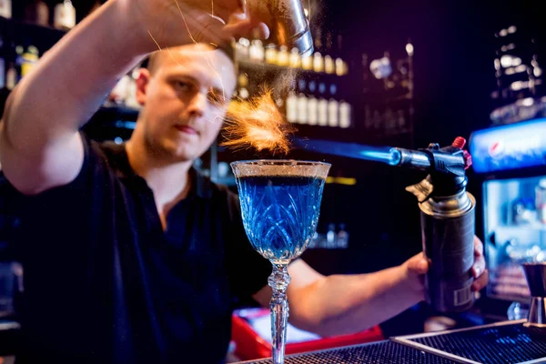 O barman faz um cocktail com um show de fogo no bar. Empregado de bar no trabalho . — Fotografia de Stock