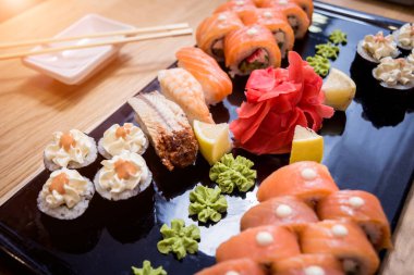 Suşi seti. Tahta bir tabakta somon, yılan balığı ve kırmızı havyarla yuvarlanıyor. Restoran.