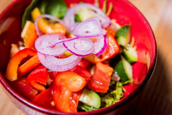 Frischer Gemüsesalat in rotem Teller auf dem Holztisch. Restaurant. — Stockfoto