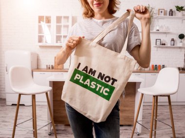 Young girl holding a cloth bag. At the kitchen. I am not plastic. 